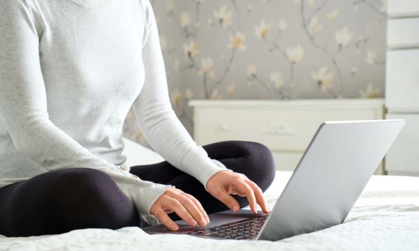 Mujer con ordenador portátil sobre la cama