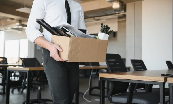 Hombre despedido del trabajo sosteniendo una caja con sus pertinencias